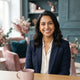 A friendly South Asian woman smiling in a professional portrait, conveying a sense of customer satisfaction.